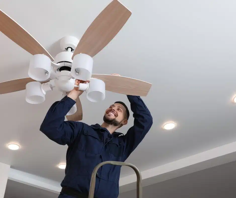 Man smiling as he installs a ceiling fan